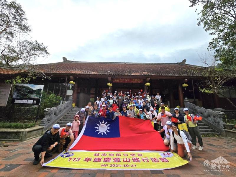 越南海防商會舉辦舉辦「慶祝中華民國113年國慶登山健行活動」，參加人員於燕子山纜車站入口拉起巨幅國旗合照