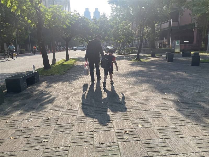 A father walks his child to school in Taipei.