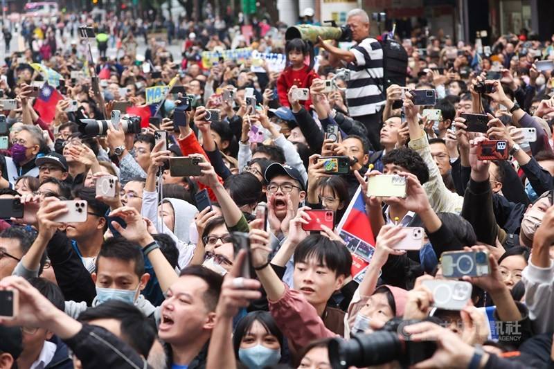 An exuberant crowd of fans hold up cameras and smartphones to snap pictures of the passing convoy in Taipei. CNA photo