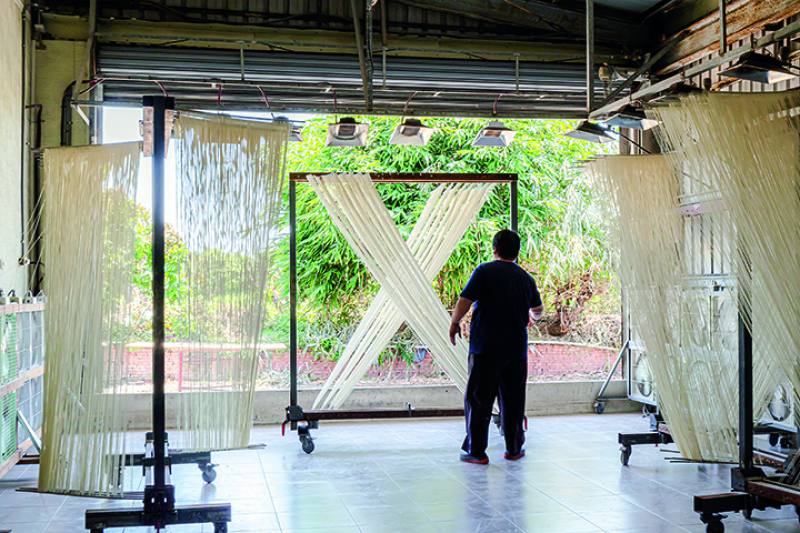 Threadlike noodles are pulled taut like bowstrings before beginning the processes of indoor drying and sun drying.