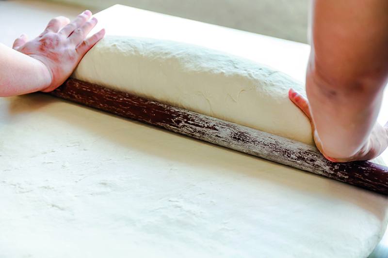 The process of making vermicelli by hand involves a complex series of steps. The photo shows the use of a rolling pin to flatten the dough.