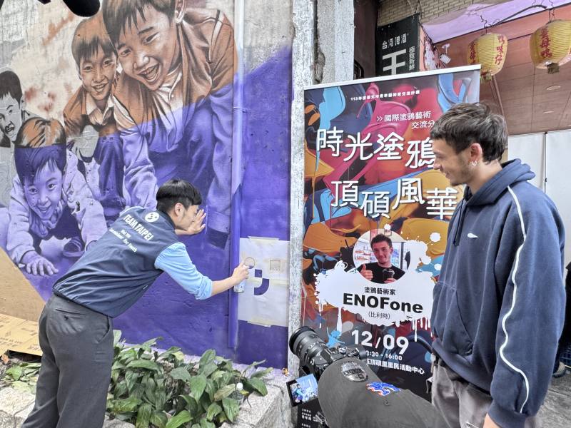 Commissioner Yin Wei of the Department for Youth (left) accepted an invitation from Belgian artist ENOFone (right) to spray-paint the Department for Youth's logo on the wall.