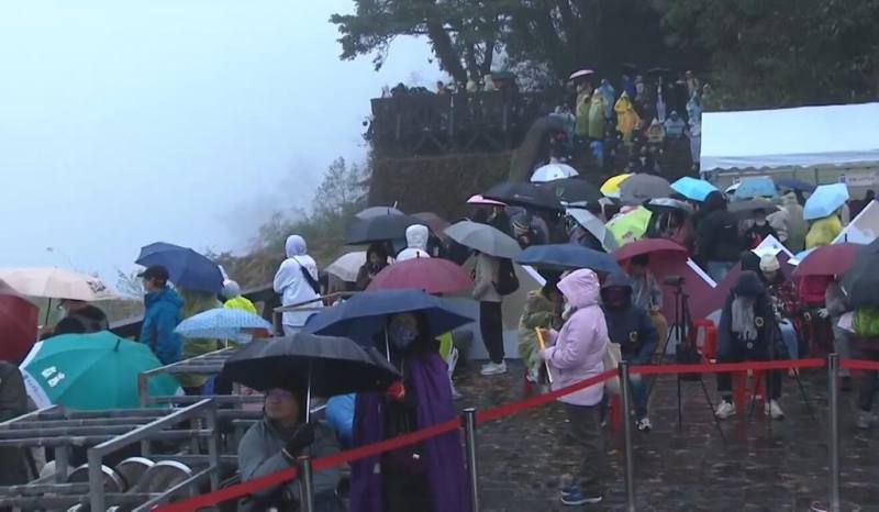 阿里山國家森林遊樂區1日清晨下雨，氣溫不到攝氏10度，不少遊客仍穿雨衣、撐傘入園迎接2025第一道曙光，雖然上午7時天色逐漸變亮，卻不見陽光露臉。（嘉義縣政府提供）