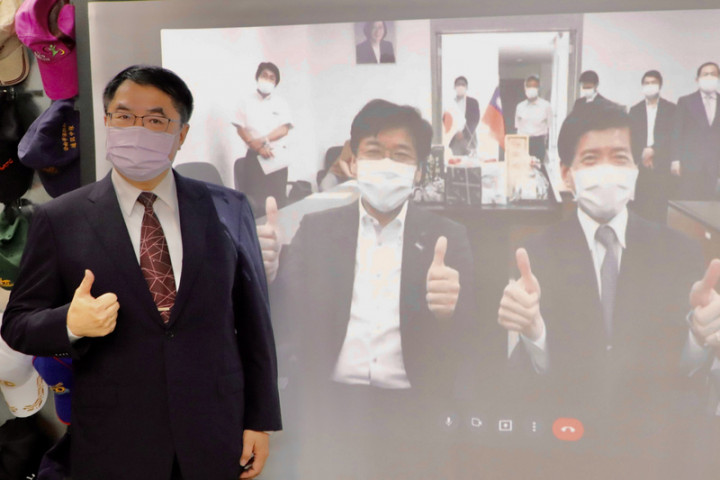 台南市長黃偉哲（左）23日下午與日本平戶市長黑田成彥（投影布幕前左）跨海視訊，互相行銷特產，進行美食外交