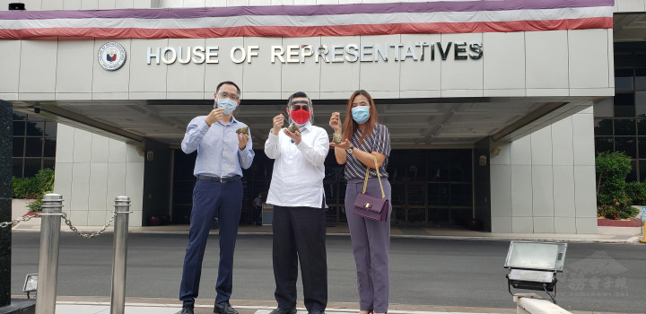 黃雅惠〈右〉與丁秋仁〈左〉贈送臺式肉粽予德查韋斯〈圖                       中〉。