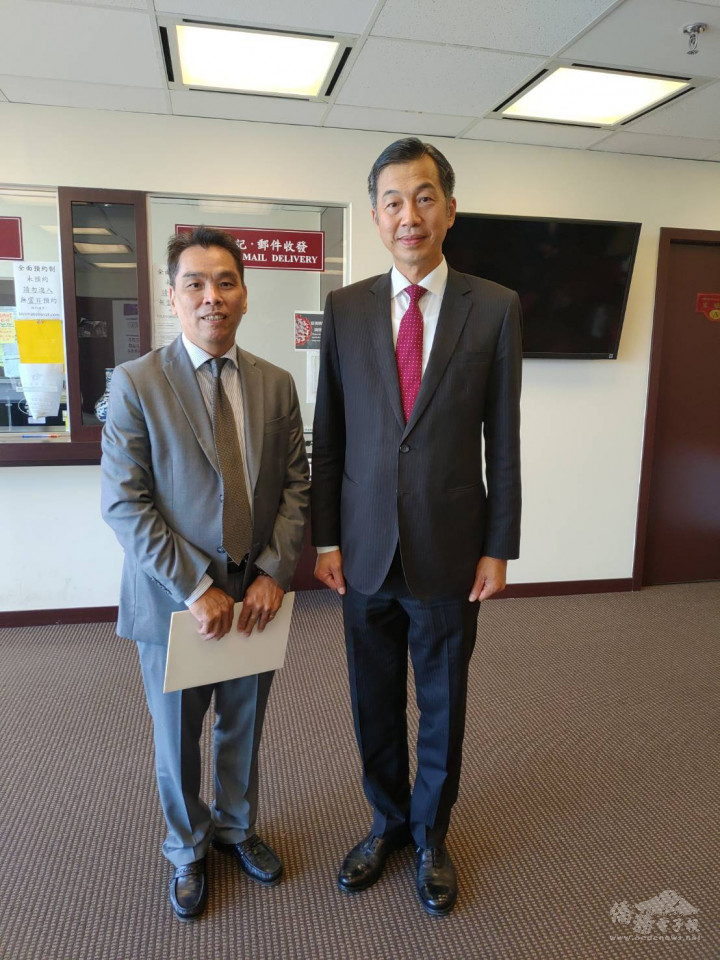 陳剛毅（右）代表僑務委員會委員長童振源頒發賀狀予新屆會長江文城（右）。