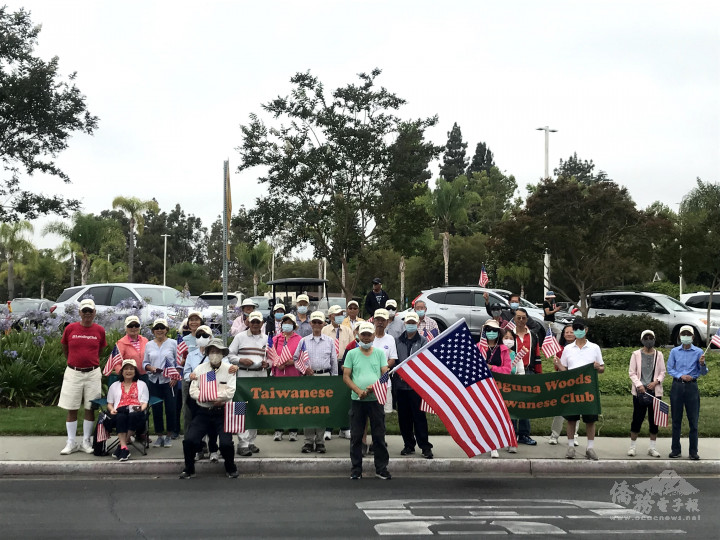 呂信賢會長(前右)手舉3×5呎大面美國國旗與其他40位鄉親手持美國手搖旗，夾道為同鄉會的車隊加油，受到社區主流及其他族裔人士的注目。  