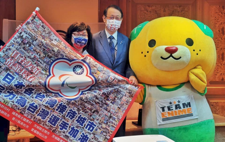 日本駐台代表泉裕泰及愛媛縣吉祥物「蜜柑犬」，將應援加油旗親自交給中華帕會。（臉書）