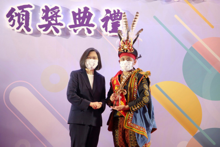 參演公視戲劇「斯卡羅」的查馬克．法拉屋樂19日晚間病逝。民進黨立委伍麗華表示，查馬克支撐到兒子樂可艾（右）北上領總統教育獎後才辭世。樂可艾20日在台北從總統蔡英文（左）手中接過獎項，隨後迅速啟程返鄉