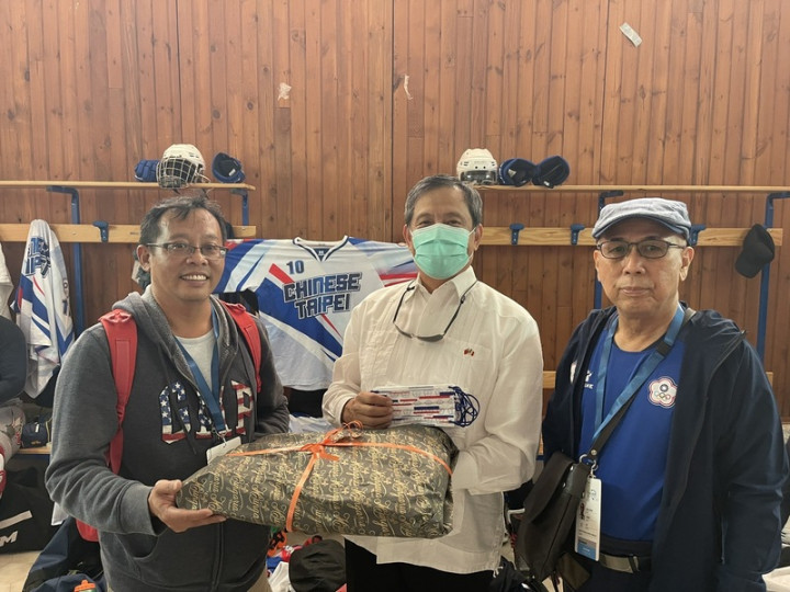 台灣直排曲棍球隊遠征義大利，力拚世錦賽進8強，駐義代表李新穎（中）到現場觀賽替台灣隊打氣，並準備羅馬老店的鹹甜點慰勞選手，由教練范元騰（左）與領隊蔣炳正（右）代表接受。（駐義代表處提供）
