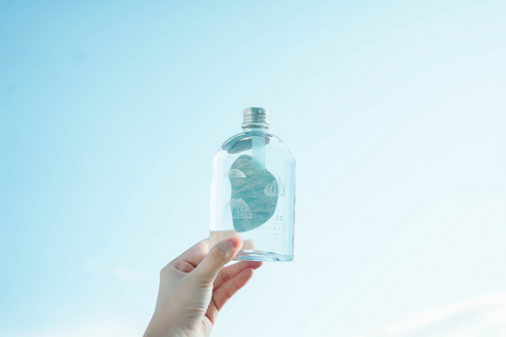 2021向海致敬概念酒瓶印上三座貝類小島，底部是馬祖湛藍海面，瓶身透出波光粼粼的大海，海洋貝類側視圖隱喻島嶼被海廢侵占，也希望人類思考海洋生物的生存處境。（食癮，拾影提供）