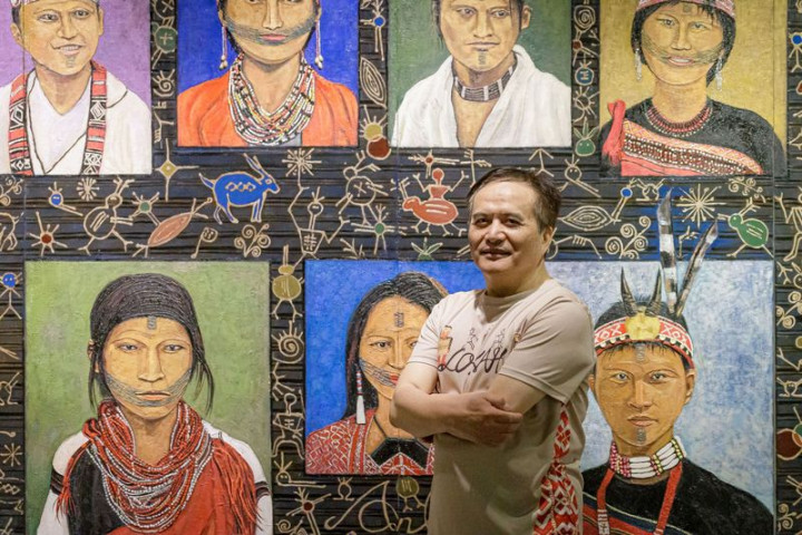 屏東美術館「我們與未來的距離－安力．給怒、宜德思．盧信雙個展」26日登場，展期至111年2月27日，展出2人近50幅作品。圖為安力．給怒和他的作品。（屏東縣政府文化處提供）