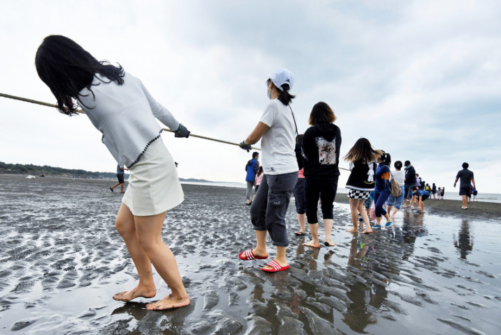 健行科技大學31日結合校內多國學生組成國際參訪團，老師帶領學生一同體驗桃園在地海洋牽罟文化，在環保志工的引領下，齊力從岸邊拉起繩索，感受前人海邊捕魚的樂趣。