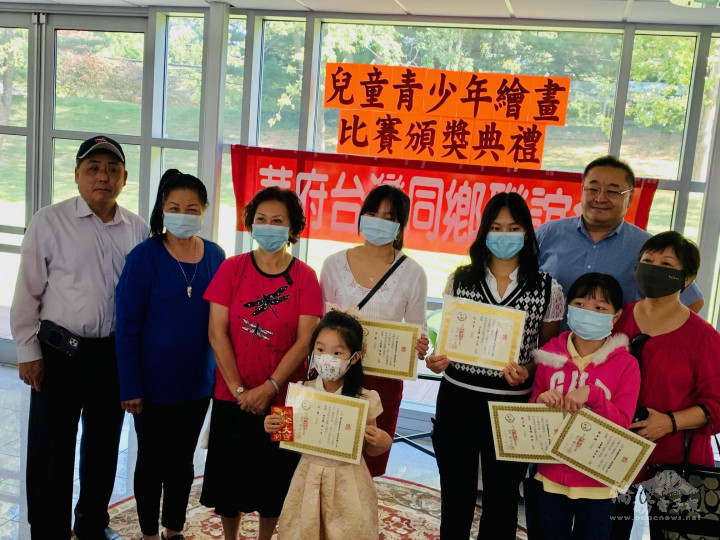劉金萍會長（左3）及臺聯會工作人員與贏得華府畫賽入選作品的小朋友們合影
