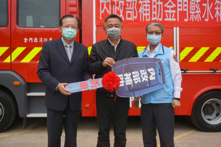 金門縣消防局獲內政部全額補助購置一輛水箱消防車，17日舉行交車典禮，消防署長蕭煥章（左）象徵性將鑰匙交給縣長楊鎮浯（中）。右為金門縣消防局長王世祿。