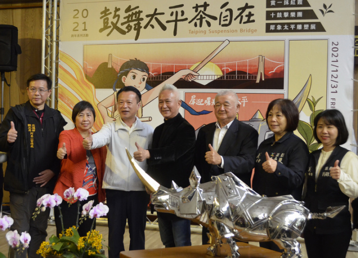 嘉義縣政府文化觀光局27日在縣府招商廣場為梅山太平社區舉辦「賞2021一抹紅霞」記者會，縣長翁章梁（左3）與梅山鄉太平村長嚴清雅（右3）邀請民眾31日至2022年1月1日到太平雲梯賞一抹紅霞、欣賞十鼓擊樂團表演及犀牛雕塑展覽。右4為藝術家施力仁。