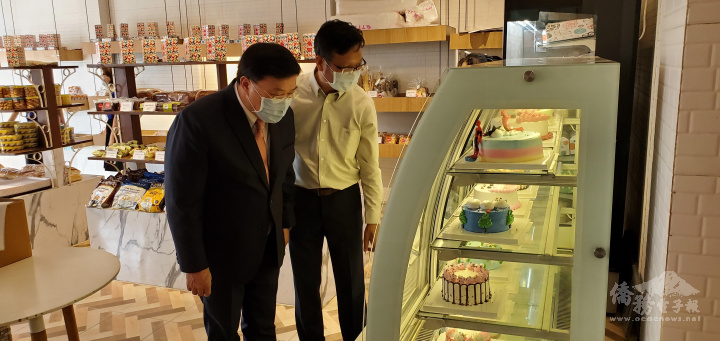 總會長溫斯郎向大使李朝成介紹店內的蛋糕產品