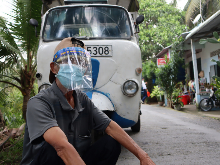 越南發話「與病毒共存」，正在起草新的疫情分級評估標準，不再過度仰賴單日新增確診數，而是參考住院與死亡人數。越南民生經濟遭COVID-19疫情重挫，圖為戴著防護面罩的摩的司機蹲在車前等待客人。