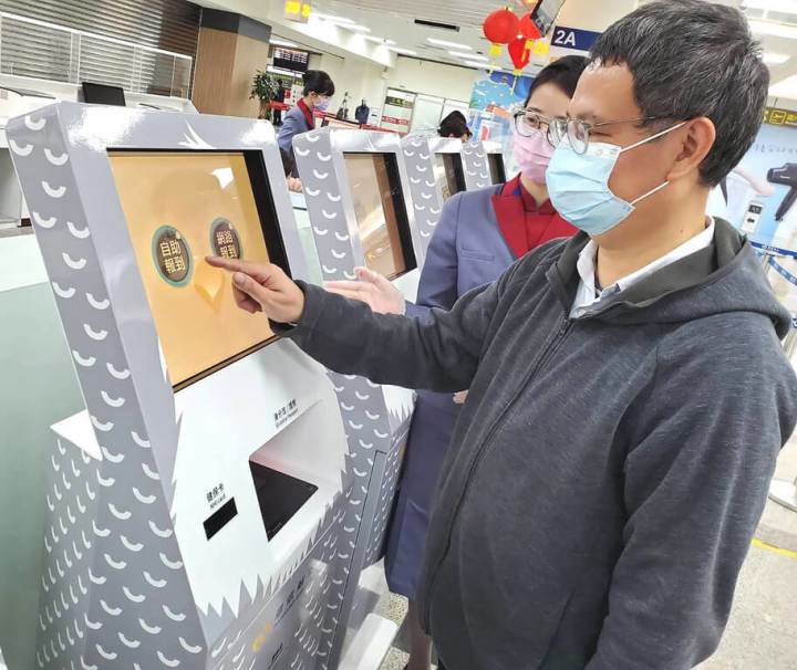 華信航空25日在松山機場啟用新引進的Kiosk自助報到機，旅客不用觸摸螢幕，用手指距離螢幕2至3公分就可感應操作。（華信航空提供）
