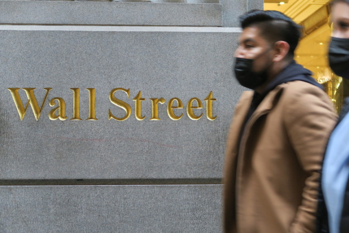全美COVID-19疫情因變異株Omicron傳播而回溫，打亂華爾街銀行讓員工重返辦公室的如意算盤。圖為民眾行經華爾街一棟商辦大樓。
