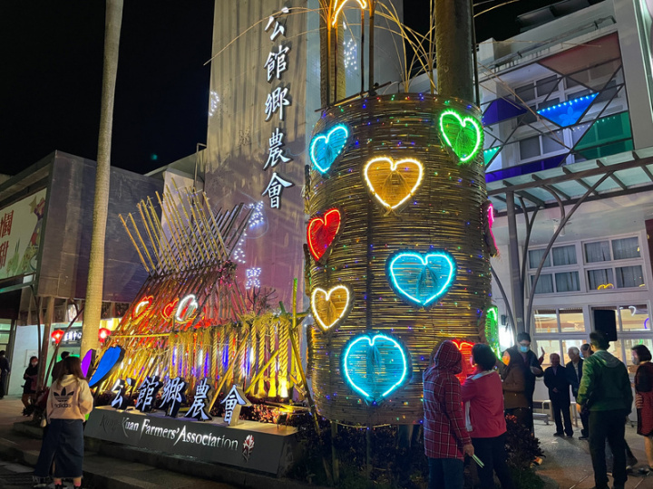 苗栗縣公館鄉農會前廣場利用稻草編織與竹編藝術搭建祈福意象裝置，夜幕低垂時，大紅燈籠及七彩燈飾照映，增添年節溫馨氣氛。