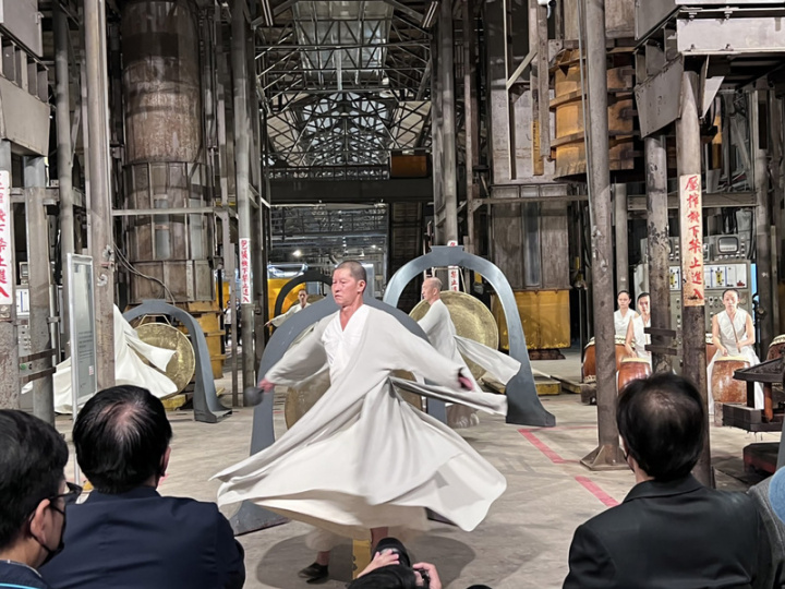 保留屏東菸葉廠再造重生的「屏菸1936文化基地」，25日開幕，邀請藝文團體「優人神鼓」在園區入口金葉廣場擊鼓祈福迎接民眾入園，舞者並以雲腳方式，穿梭在大型加工機具間，用鼓聲、銅鑼等不同樂器屬性，創造空間音樂感，在舞者忽快忽慢的移動步伐當中，遊走空間，也引領觀眾穿越時間長河，平靜享受空間美好。（屏東縣政府文化處提供）