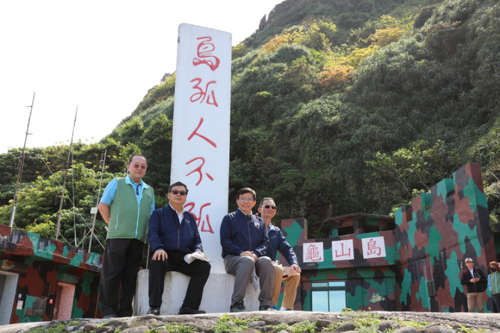 交通部長王國材（右2）12日與觀光局長張錫聰（左2）等人登上龜山島，視察環湖步道、軍事坑道等觀光建設景點，並在昔日駐軍所立標語「島孤人不孤」前留影。（交通部觀光局提供）