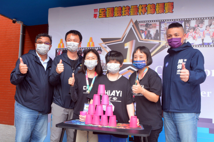 嘉義市育人國小重度弱視學生陳采稼（右3）12日北上參加111年全國競技疊杯錦標賽，與嘉義市教育處長林立生（左）、校長楊家豪（左2）及老師教練等人一起合影。