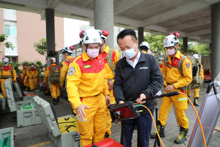 日本福島外海發生強震，嘉義縣消防局特種搜救隊集結待命救援，縣長翁章梁（前右）17日上午校閱特搜隊，並聽取影音生命偵測器、支撐器、破壞油壓器材等各類救災設備如何操作。（嘉義縣政府提供）