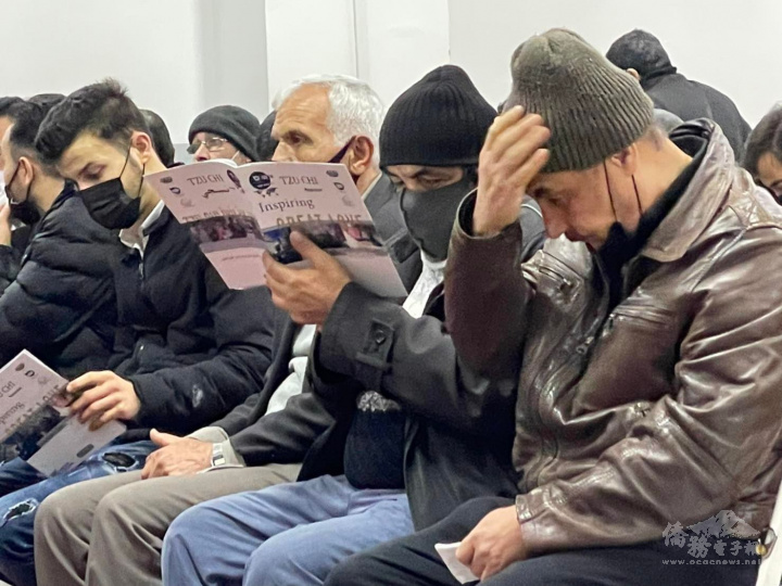 拿到憑證後的敘利亞鄉親坐在椅子上閱讀月刊，等待發放