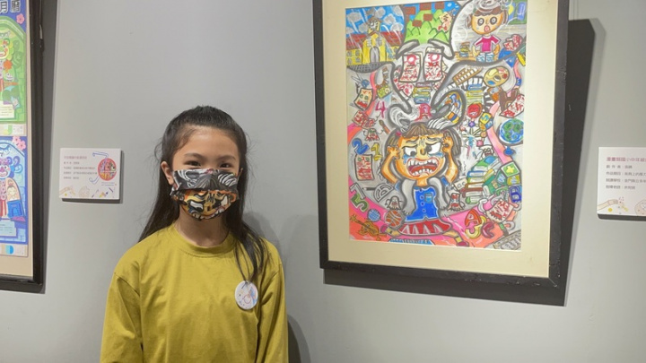 110學年度全國學生美術比賽優勝作品30日起在金門縣文化局展出，多年國小張晴在此次比賽以「我肩上的壓力鬼」獲得佳作，她戴著以自己作品製成的口罩合影。
