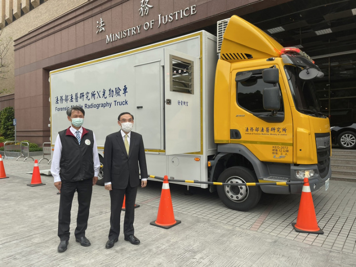 法務部6日舉行媒體茶敘，由法醫所進行專題報告，並將高機動性、造價新台幣1500萬元的X光勘驗車開到法務部前展示，部長蔡清祥（右）及法醫所長侯寬仁（左）在車前開心合影。
