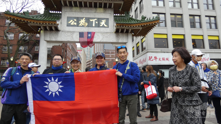 來波士頓參加馬拉松賽的跑者，紛紛在華埠牌樓前拉開國旗拍照留念