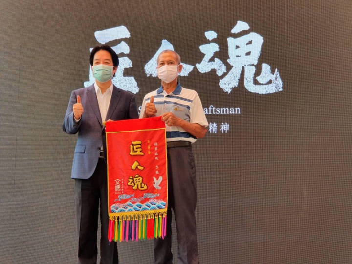 文化總會「匠人魂」系列影片第33集紀錄屏東草編工藝師李龍（右），6日舉行「編織福氣的稻草人」發布紀者會，擔任文總副會長的副總統賴清德（左）頒發「匠人魂」錦旗給李龍，表彰職人精神。