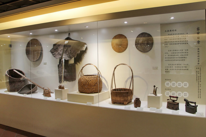 新北市客家文化園區即日起至6月15日展出「見古說今－園區典藏文物展」，重現客家先民生活智慧，現場展示「氣死貓」吊籃、魚簍、蓑衣、斗笠、畚箕、扁擔等生活文物。（新北市客家局提供）