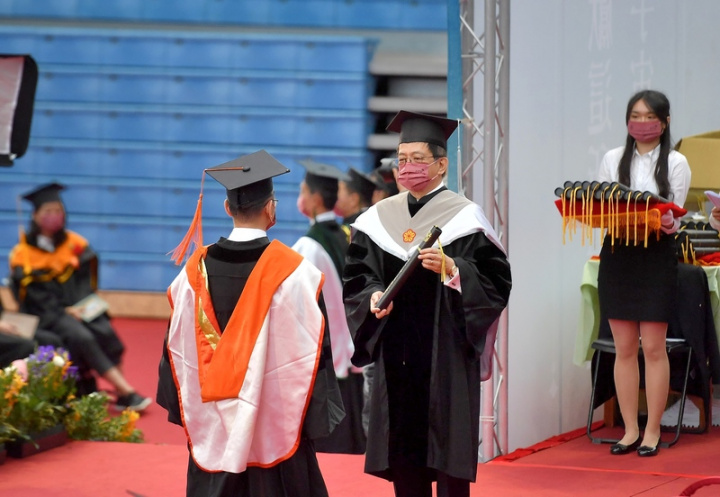 國立台灣大學21日上午在綜合體育館舉行110學年度 畢業典禮，校長管中閔（中）頒發畢業證書給畢業 生，獻上祝福。