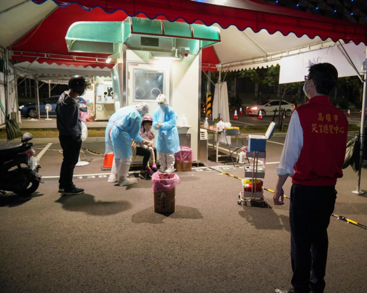 高雄市政府針對18歲以下快篩陽性且有症狀兒童，在9家醫院、4處社區採檢站開設特別門診，除進行PCR採檢，也由小兒科醫師現場診療、評估是否需要住院。市長陳其邁（右）6日晚間到高雄展覽館旁新光停車場社區篩檢站，視察門診整備情形。（高雄市政府提供）