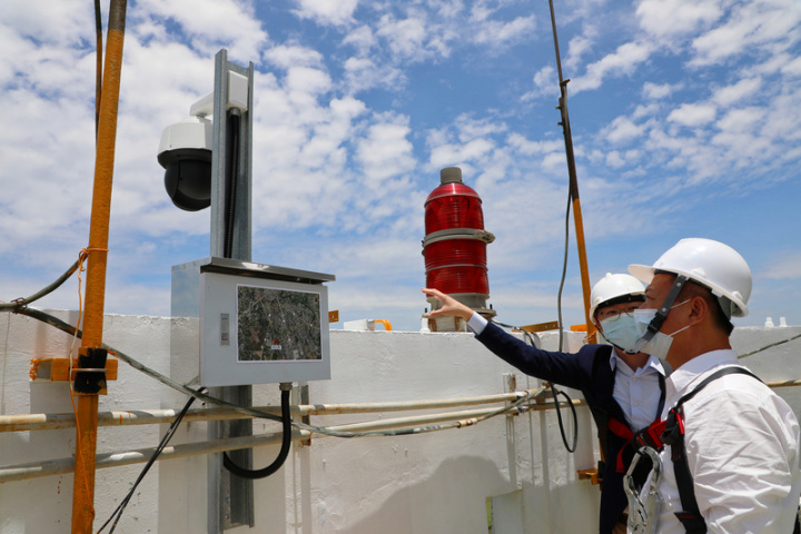 嘉義縣環保局在鹿草焚化爐120公尺高煙囪設置AI煙霧探測系統24小時360度監控並自動辨識空污，縣長翁章梁（右）18日也到場聽取簡報，乘座電梯再攀爬上120公尺高煙囪頂端，瞭解AI系統如何運作。（嘉義縣政府提供）