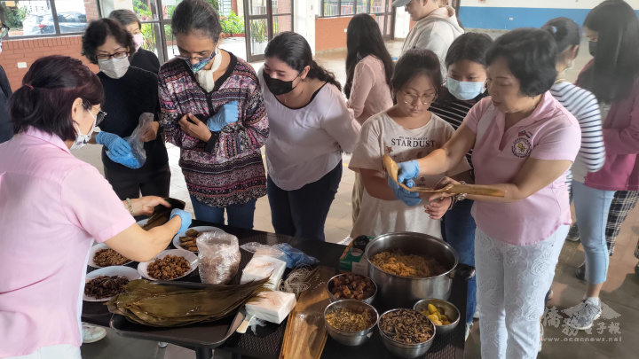 現場小朋友及國合會華語學生，依序上前練習如何包粽子