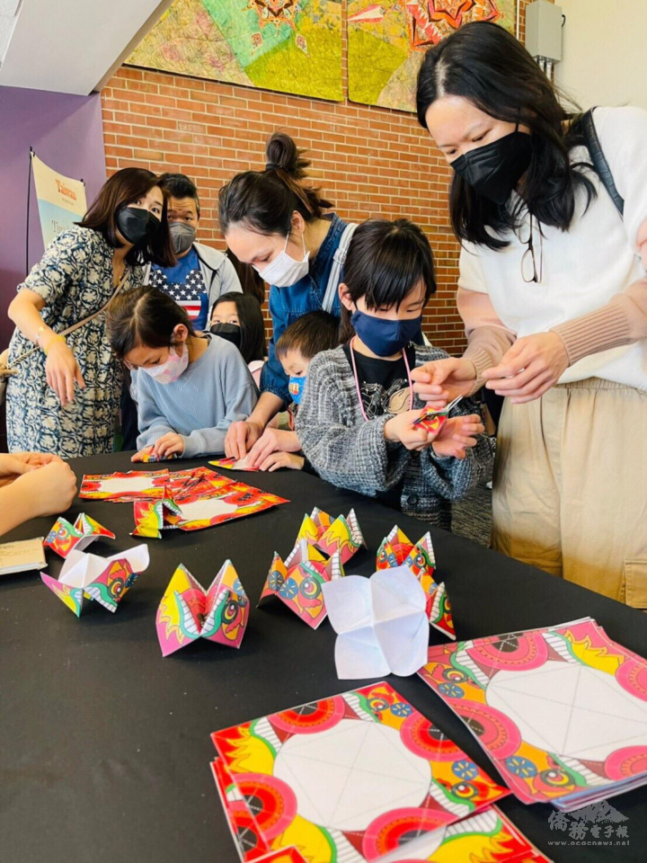 舞獅隊的攤位帶著小朋友摺紙獅頭