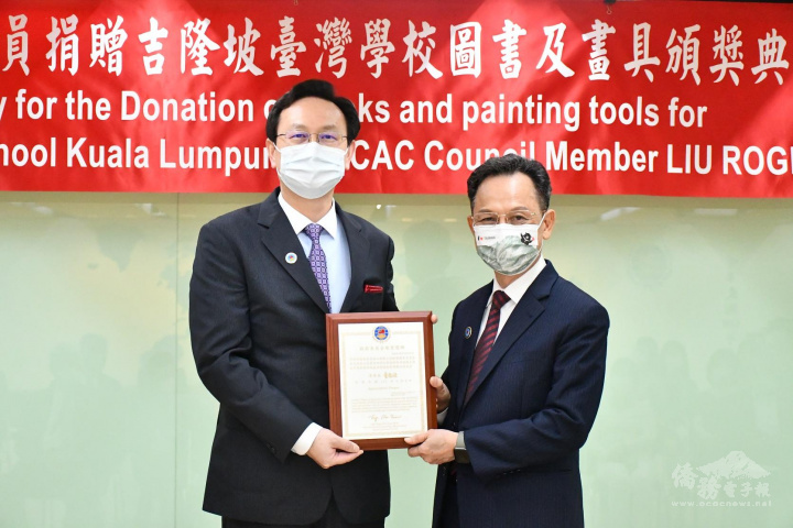 童振源(左)頒贈銀質獎牌給僑務委員劉惟祥(右)