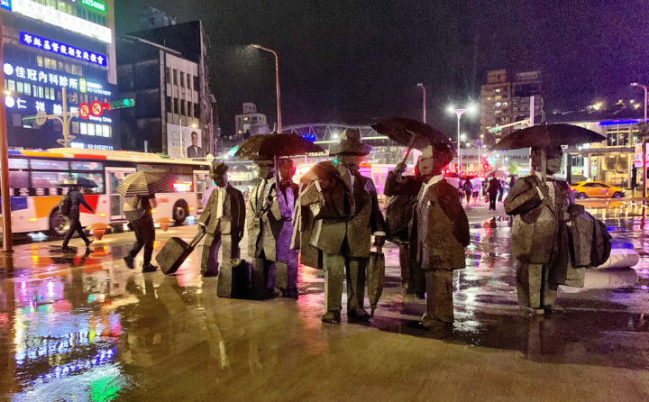 朱銘美術館以「人間系列－紳士」參與2022城市博覽會，雕塑們站在基隆國門廣場拉行李、撐傘，像極在雨都中準備踏向未知或返回家門的旅人。（朱銘美術館提供）