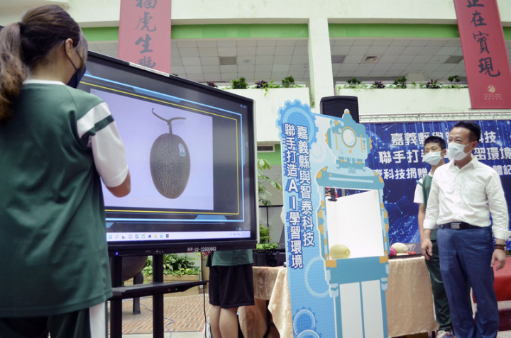 智泰科技公司14日捐贈3000多套圖像辨識軟體給嘉義縣各級學校，打造AI學習環境，竹崎高中學生現場利用攝影鏡頭搭配圖像辨識軟體，分辨嘉義縣生產的優良蔬果，嘉義縣長翁章梁（右）在旁聽取學子解說。