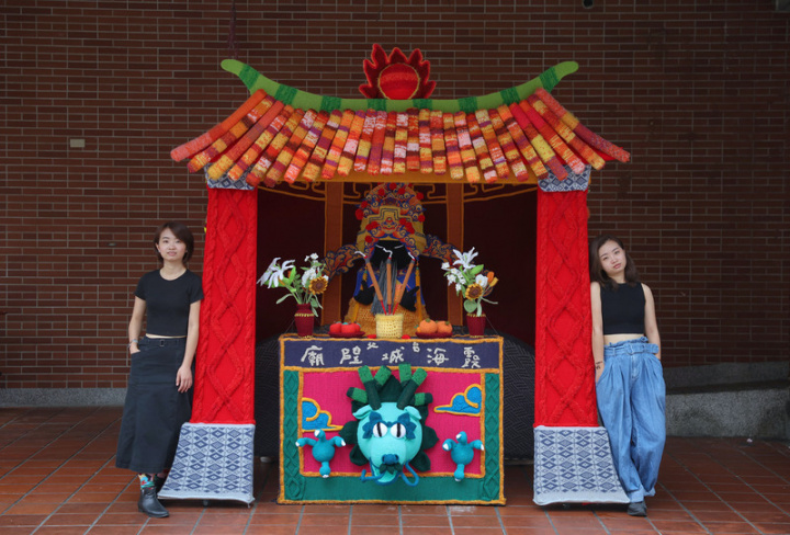 雙胞胎姊妹陳亞琦（右）及陳亞筑（左）以毛線創作裝置藝術「城隍毛線廟」，逾2米高的毛線廟有毛線供花及毛線筊杯，城隍爺還會比Rock手勢，趣味十足。