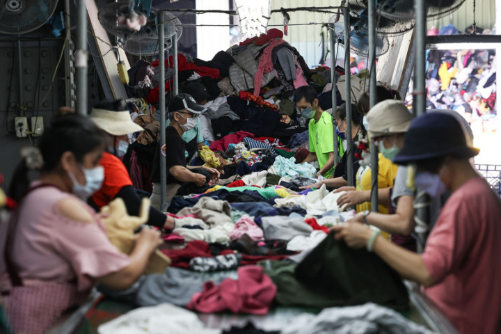 新北市五股區的正川回收廠員工正幹練地分類整理舊衣。