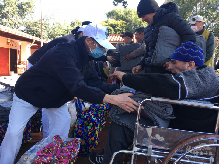 慈濟師兄姊與志工們向受惠戶送上慈濟環保毛毯與食物籃