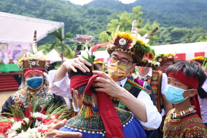 高雄市長陳其邁（中後）31日受邀前往茂林部落參加 小米豐收祭，現場為部落成年青年別上百合花，祝賀 勇士們成為真正的男人。 （高雄市政府提供）