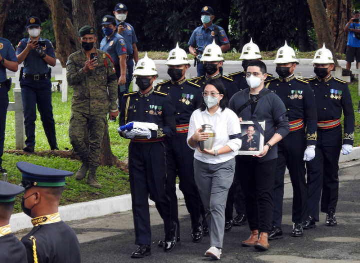 位於馬尼拉的菲律賓國家英雄墓園9日舉行前總統羅慕斯國葬儀式，羅慕斯家人捧著羅慕斯骨灰罈和遺照進入會場。
