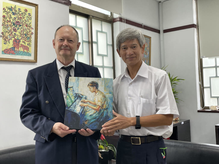 南非駐台代表安德生（Hugh Graham Anderson）（左）日前再度參訪台灣藝術教育館，盼透過兒童畫跨越國界，讓台灣和南非有進一步合作機會。圖為藝教館長李泊言（右）致贈梁丹丰作品複製畫給安德生。（台灣藝術教育館提供）