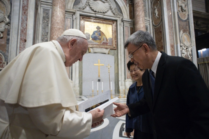  前副總統陳建仁（右）獲得教宗方濟各（左）接見時，致贈記錄了天主教神父修女在台奉獻故事的書籍「天使傳愛」，教宗仔細閱讀並露出開心笑容。（教廷官方攝影網站）